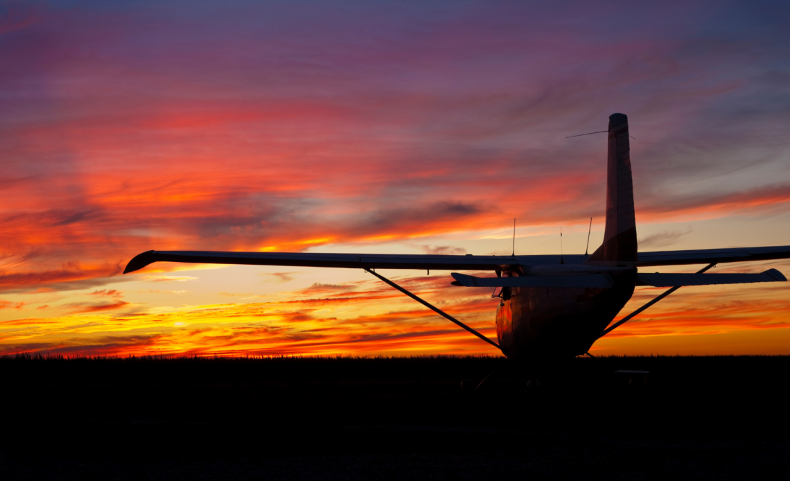 small plane silhouette in front of beautiful sunset