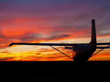 small plane silhouette in front of beautiful sunset