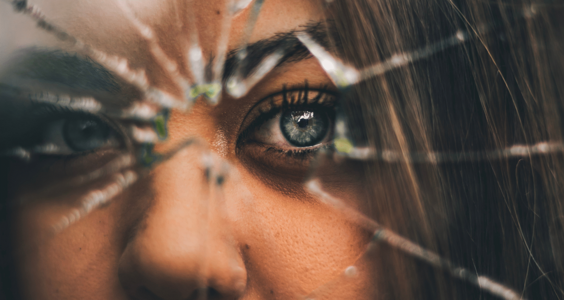 close up of woman's face behind a cracked and broken window