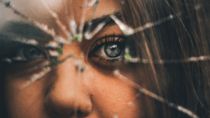 close up of woman's face behind a cracked and broken window
