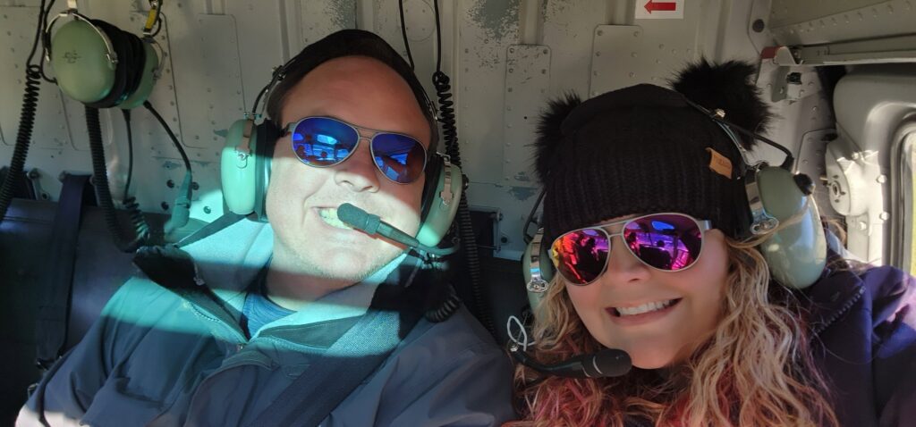 Ivy and her husband, Sweet-D, sitting in a helicopter wearing headphones.